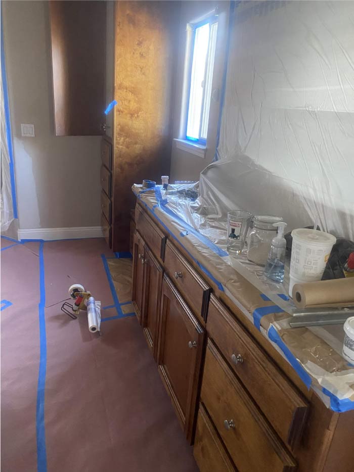 A set of bathroom cabinets before professional painting, featuring worn, outdated wood with visible scratches, faded color, and chipped edges. The dull finish makes the cabinets look aged and out of place in the bathroom’s design. The lack of a fresh coat of paint diminishes the overall cleanliness and modern appeal of the space. This image highlights the need for a professional painting service to revitalize the cabinets with a sleek, durable finish.
