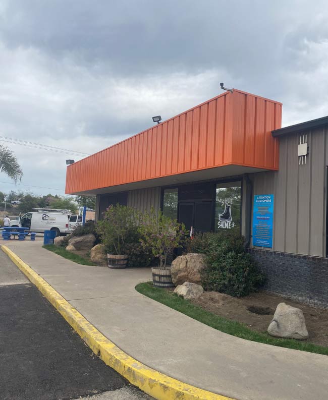 A commercial storefront before professional painting, with faded and peeling paint that makes the business look dated and uninviting. The exterior walls show signs of wear, including discoloration and minor cracks, diminishing the store’s curb appeal. The signage and trim blend into the dull background, failing to attract customers. This image highlights the need for a professional exterior painting service to enhance the storefront’s appearance and create a welcoming, modern look.