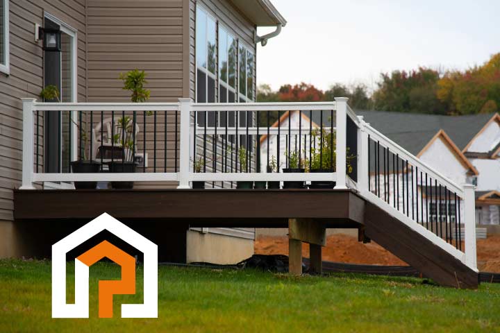 A freshly stained dark brown wooden deck with white railings and black balusters, providing a clean and protected outdoor space for a residential home.