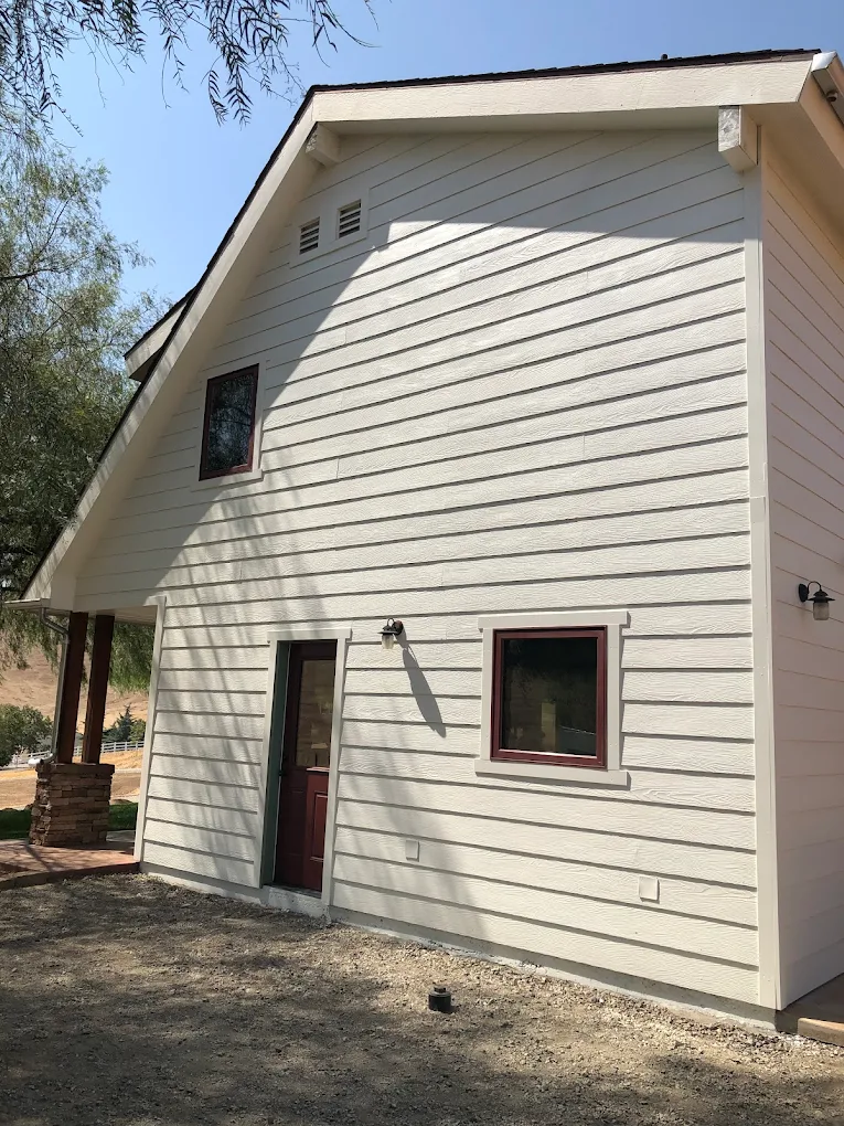 Two-story residential home with cream-colored horizontal lap siding and dark mahogany window trim completed by an exterior painting in Sanger specialist.